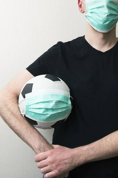 Tıbbi maske takmış futbol oynayan bir adam. Virüs 2020
