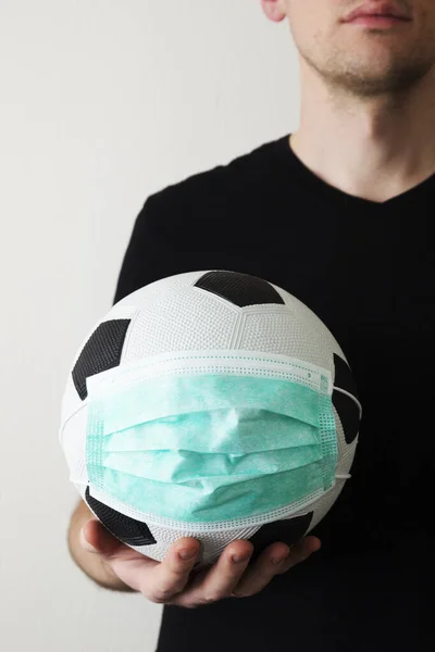 Tıbbi maske takmış futbol oynayan bir adam. Virüs 2020