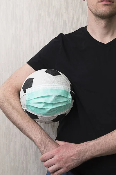 Tıbbi maske takmış futbol oynayan bir adam. Virüs 2020