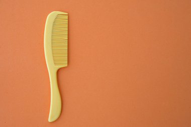 Çocuklar plastik saç tarağı sarısı, turuncu arka plan yakın plan.