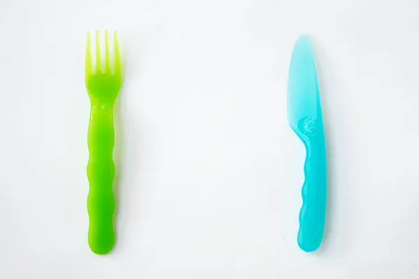 Пластиковая вилка зеленый и нож синий белый фон вид сверху — стоковое фото