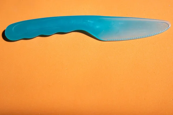 Plastik bıçak mavi turuncu arka plan üst görüntüyü kapat