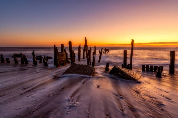 Maré de saída lava em torno da velha defesa do mar em Spurn Point — Fotografia de Stock