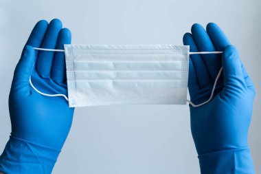 Doktor erkek, tıbbi maske takmaya hazır nitril mavi tıbbi eldiven giyiyor. İzole edilmiş beyaz arkaplana yakınlaş. 