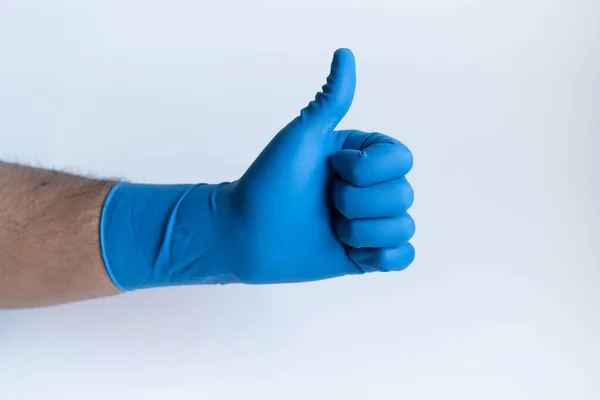 男性医師の手のジェスチャーを親指のサインを表示します 医療用青いニトリル手袋を着用してください 白を背景に フロントビュークローズアップ — ストック写真