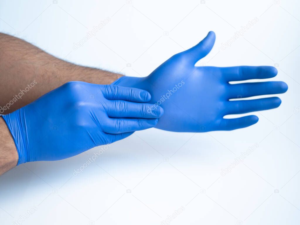 Male doctor hands wearing nitrile blue medical protection gloves. Front view photography on white studio background.