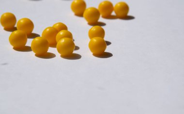 Beyaz arka planda sarı vitaminler ve gölgeler.