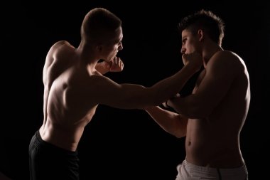 İki genç gömleksiz savaşçıları siyah arka plan üzerine poz