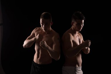 İki genç gömleksiz savaşçıları siyah arka plan üzerine poz