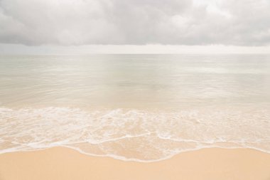 Gri bulutlar ile sahilde yumuşak dalgalar