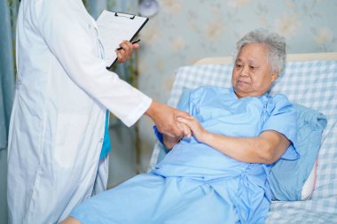 Doktor teşhis ve asya yaşlı yaşlı kadın ile pano üzerinde not hakkında konuşurken hemşirelik hastanesi koğuşunda yatakta yatarken: sağlıklı güçlü tıbbi kavram
