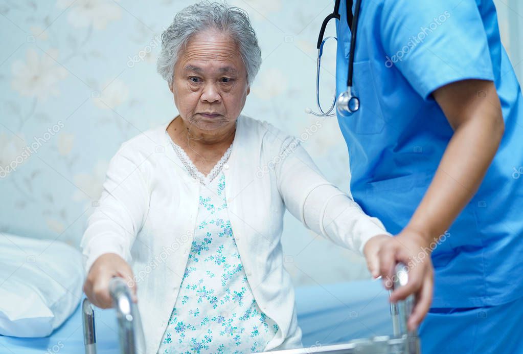 Asian nurse physiotherapist doctor care, help and support senior or elderly old lady woman patient walk with walker at hospital ward : healthy strong medical concept