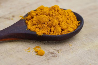 Ahşap arka planda zerdeçal tozu bitkisi.