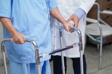 Doktor yaşlı ya da yaşlı kadın hastaların hemşire koğuşunda Walker ile yürümelerine yardım ediyor: sağlıklı güçlü tıbbi konsept.