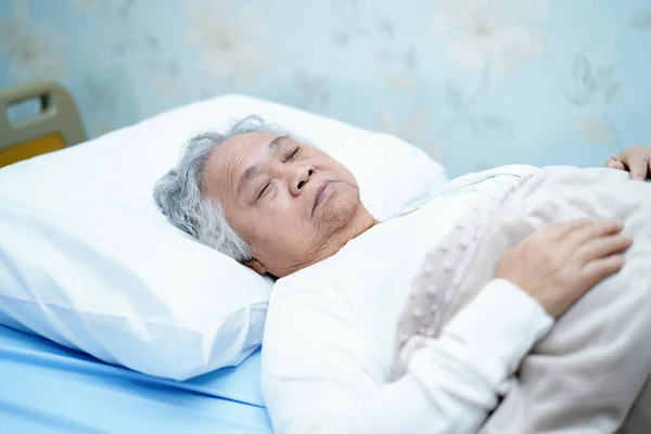 Asian senior or elderly old lady woman patient smile bright face with strong health while lying on bed in nursing hospital ward : healthy strong medical concept