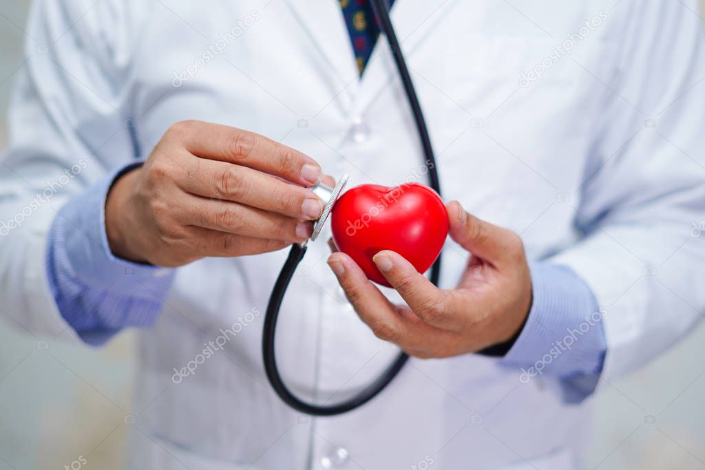 Doctor holding stethoscope and red heart in his hand in nursing hospital ward : healthy strong medical concept
