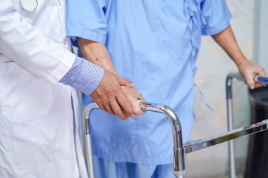 Doktor yaşlı ya da yaşlı kadın hastaların hemşire koğuşunda Walker ile yürümelerine yardım ediyor: sağlıklı güçlü tıbbi konsept.