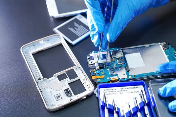 Asian Technician repairing micro circuit main board of smartphone electronic technology : computer, hardware, mobile phone, upgrade, cleaning concept