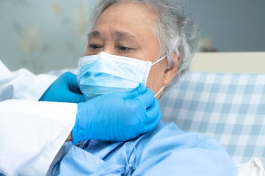 Doktor, enfeksiyonu korumak ve Novel Coronavirus 'u (2019-nCoV) öldürmek için hastanede maske takan yaşlı ve yaşlı kadına yardım ediyor..