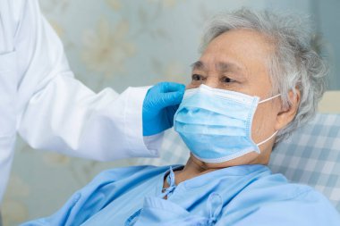 Doktor, enfeksiyonu korumak ve Novel Coronavirus 'u (2019-nCoV) öldürmek için hastanede maske takan yaşlı ve yaşlı kadın hastalara yardım ediyor..