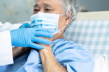 Doktor, enfeksiyonu korumak ve Novel Coronavirus 'u (2019-nCoV) öldürmek için hastanede maske takan yaşlı ve yaşlı kadın hastalara yardım ediyor..