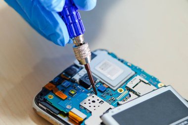 Technician repairing micro circuit main board of smartphone electronic technology : computer, hardware, mobile phone, upgrade, cleaning concept.    
