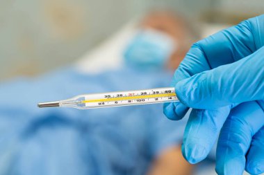 Asyalı yaşlı ya da yaşlı kadın hastanın yüz maskesi taktığını ölçmek için dijital termometre tutan doktorun hastanede ateşi var: sağlıklı güçlü tıbbi konsept.