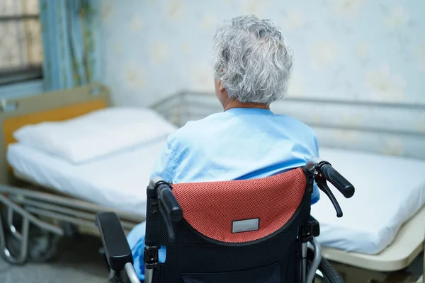 亚洲老年老年妇女病人坐在护理病房靠近病床的轮椅上 健康而有力的医疗理念 — 图库照片