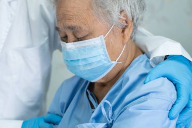 Doktor, güvenlik enfeksiyonunu korumak ve Novel Coronavirus 'u (2019-nCoV) öldürmek için hastanede maske takan yaşlı ve yaşlı bir kadına yardım ediyor..