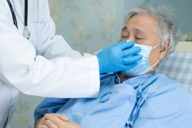 Doktor, güvenlik enfeksiyonunu korumak ve Novel Coronavirus 'u (2019-nCoV) öldürmek için hastanede maske takan yaşlı ve yaşlı bir kadına yardım ediyor..