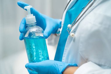 Hastanın güvenlik enfeksiyonunu korumak ve Roman Coronavirus Covid-19 virüsünü, bakterileri ve mikropları öldürmek için mavi alkol dezenfektanı tutan doktor..