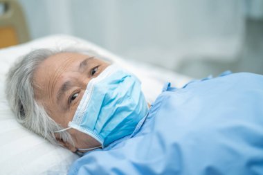 Güvenlik enfeksiyonunu korumak ve Roman Coronavirus Covid-19 virüsünü öldürmek için hastanede maske takan yaşlı ve yaşlı bir kadın..