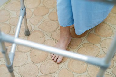 Asyalı, yaşlı, yaşlı kadın hasta, hemşire hastanesi koğuşunda Walker 'la birlikte yürüyor. Sağlıklı, güçlü bir tıbbi konsept. 