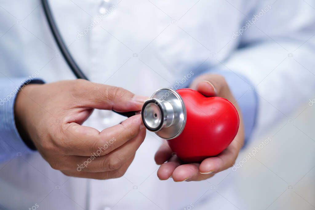 Doctor holding red heart in his hand in nursing hospital ward : healthy strong medical concept.