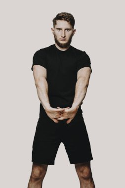 Sakallı genç sportif adam el kasları bir WHI üzerinde uzanır.