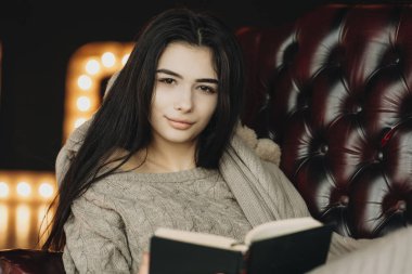 Bir kitap okuma ve kameraya seyir güzel genç kız.  