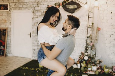 Onun sevgilisi onun kollarında tutarak ve gülümseyen yakışıklı sakallı adam 