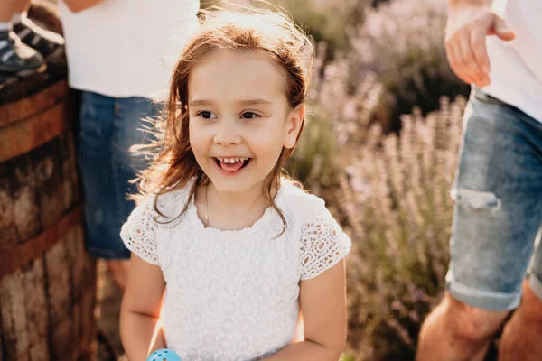 Uma menina pequena encantadora posando em um campo de lavanda está sorrindo feliz e ter alegria cercada por muitas emoções — Fotografia de Stock