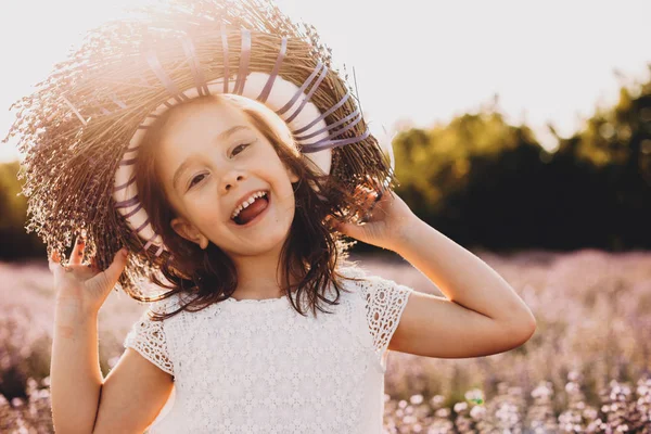 Uma pequena menina caucasiana alegre vestindo uma coroa de flores está jogando alegremente no calor do sol — Fotografia de Stock