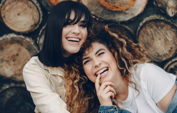La photo rapprochée de deux femmes magnifiques souriantes posant sur un fond boisé — Photo