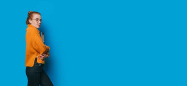 Çalışkan kızıl saçlı bir öğrenci, büyük boşluğun yanında duran üniversite eşyalarının tanıtımını yapıyor.