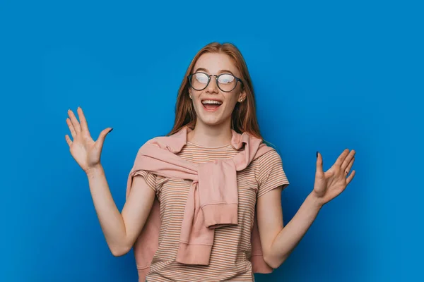 Ein fröhliches Mädchen mit roten Haaren und emotionalem Lächeln gestikuliert, als wäre sie mit der ganzen Arbeit fertig und würde sich entspannen. — Stockfoto