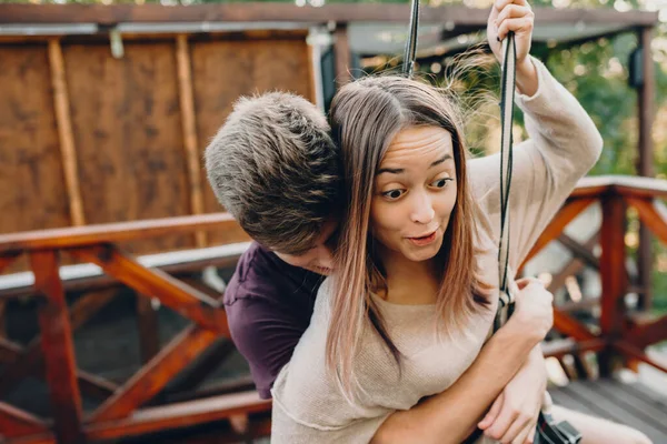 Um menino caucasiano cuidadoso abraçando sua namorada enquanto ela se sente com medo de uma viagem de ropeway — Fotografia de Stock