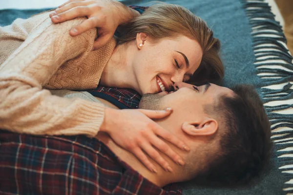 Doce mulher com sardas está beijando seu marido durante uma manhã fria em seu apartamento — Fotografia de Stock