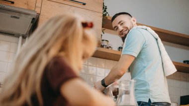 Gülümseyen beyaz çocuk, mutfakta ödev yaparken küçük kız kardeşine bakıyor.