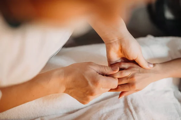 Médico caucasiano atento e concentrado está massageando cuidadosamente clientes dedos segurando sua palma pequena — Fotografia de Stock