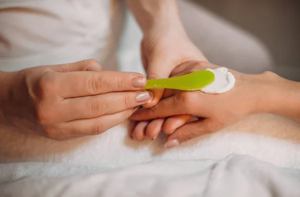 Creme especial aplicado na mão dos clientes antes de iniciar o procedimento de massagem e cuidados com a pele — Fotografia de Stock