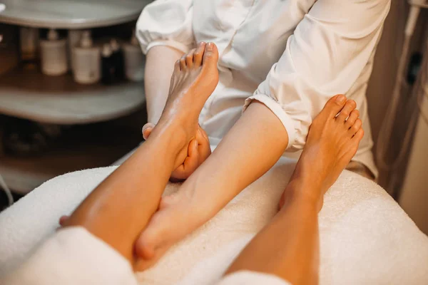 Ragazza caucasica sdraiata mentre un medico messaggia le gambe in un salone spa — Foto Stock