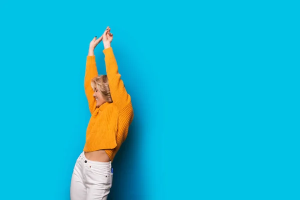 Preciosa chica caucásica con cabello rubio bailando sobre un fondo azul con espacio en blanco — Foto de Stock