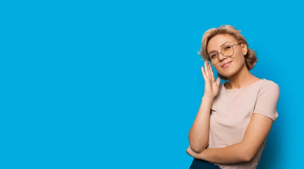 Nádherná dáma při pohledu přes brýle při reklamě něco na modrém pozadí s volným prostorem — Stock fotografie